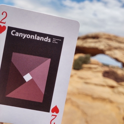 playing card in front of a rock archway at Canyonlands National Park