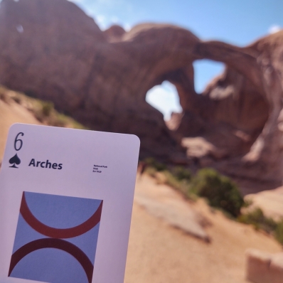playing card in front of a rock archway at Arches National Park